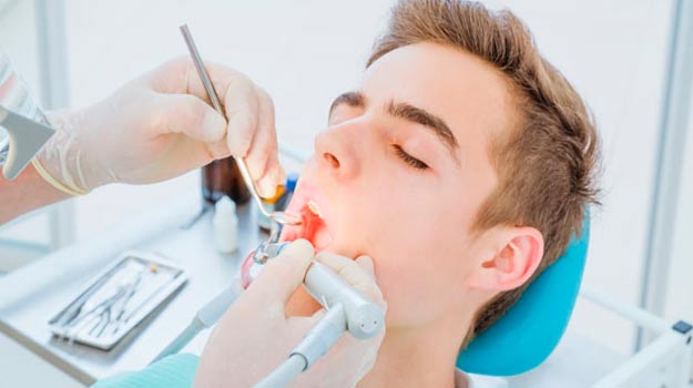 Young man receiving a root canal in Vancouver from a dentist using specialized tools