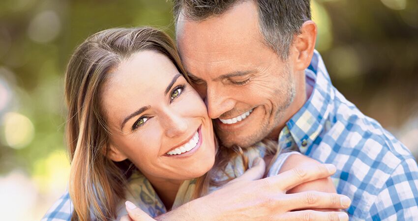 Couple embraces and smiles to show teeth after dental bonding treatment