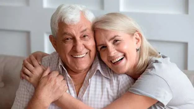 An elderly couple with bright smiles, showcasing their happiness with dentures in Vancouver