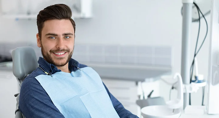 A smiling man in a dental chair at a modern clinic, representing dental services in Vancouver, BC.