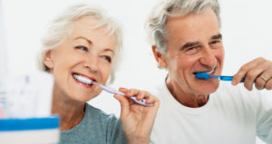 Elderly couple brushes teeth in mirror