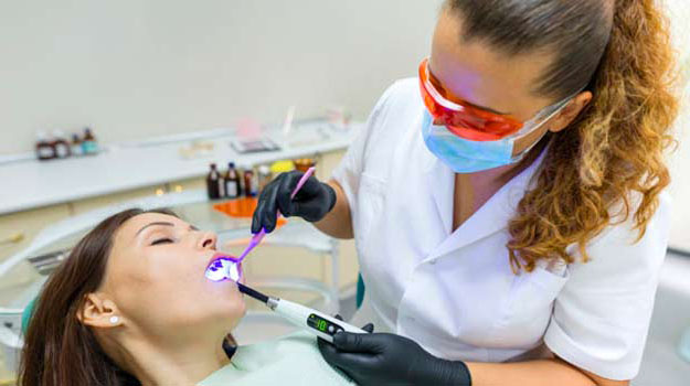 A Female Patient Getting Her Teeth Cleaned By Female Dentist
