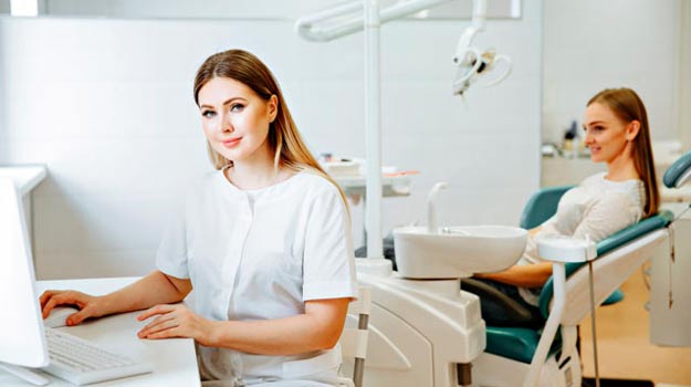 A Beautiful Female Dentist Examining Report On A Computer